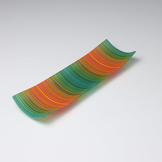 A decorative shallow rectangular boat shaped glass plate with raised corners and a  colourful ColourWave stripe patterns showing key colours of taal and orange with highlights of yellow and purple.