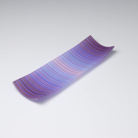 A decorative shallow rectangular boat shaped glass plate with raised corners and a  colourful ColourWave stripe patterns showing key colours of purple, pale blue and pink