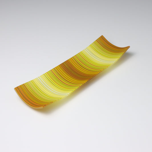 A decorative shallow rectangular boat shaped glass plate with raised corners and a  colourful ColourWave stripe patterns showing key colours of bronze, yellow and white