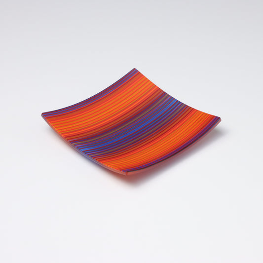 A decorative square shallow glass plate with raised corners and a  colourful ColourWave stripe patterns showing key colours of purple, orange and blue