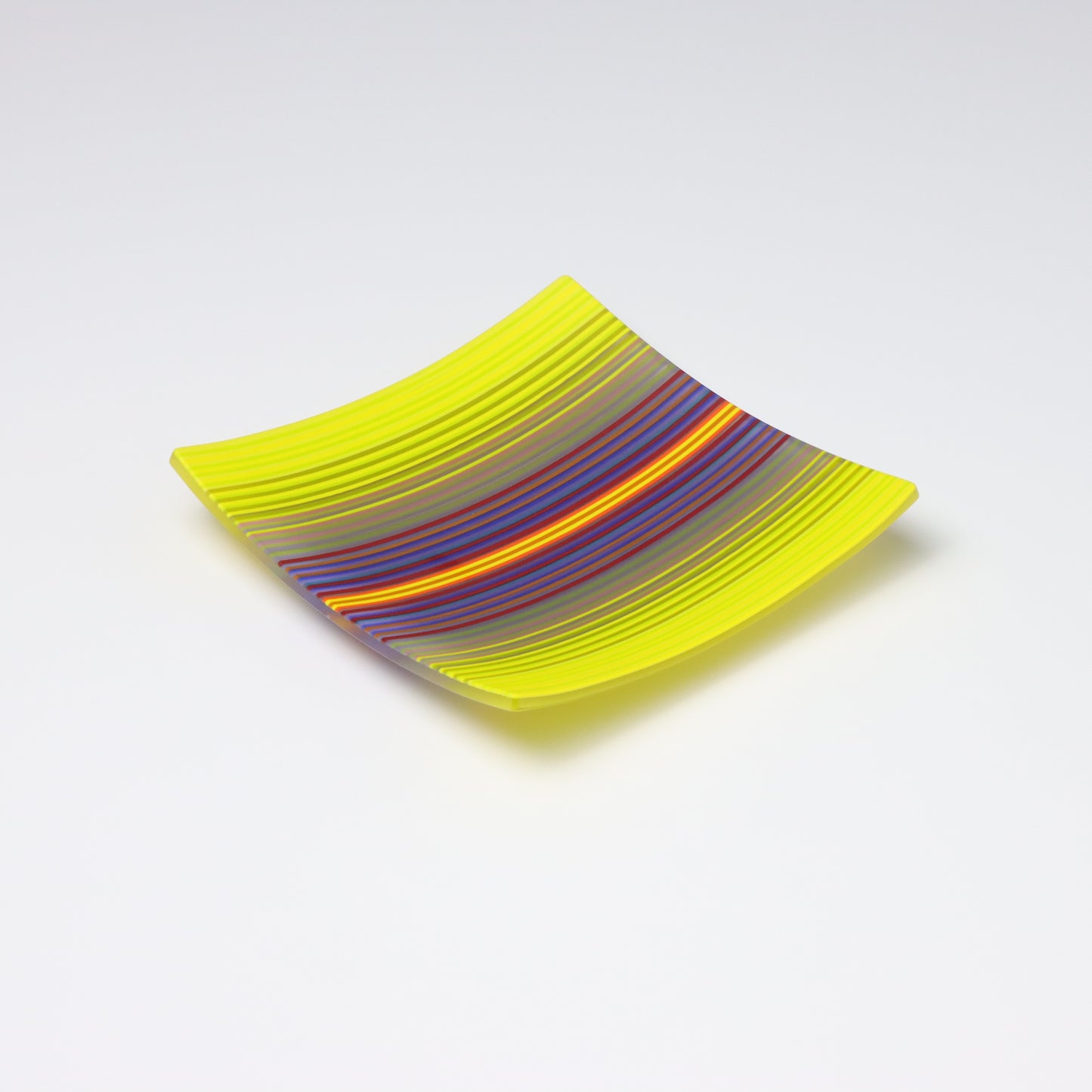 A decorative square shallow glass plate with raised corners and a  colourful ColourWave stripe patterns showing key colours of yellow, and purple, blue  and red.