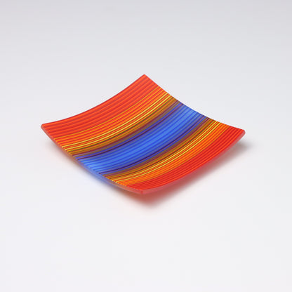 A decorative square shallow glass plate with raised corners and a  colourful ColourWave stripe patterns showing key colours of red, orange and bright blue